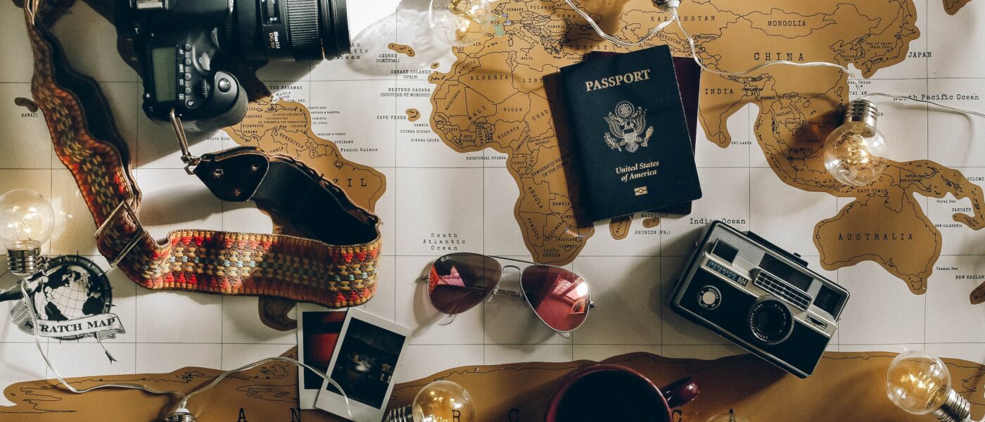 Map covered with items, including sunglasses, phone, cameras, passports, and more.