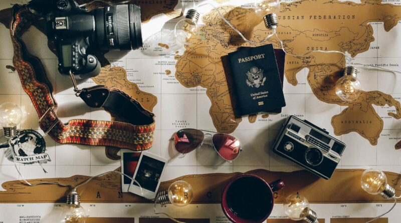 Map covered with items, including sunglasses, phone, cameras, passports, and more.