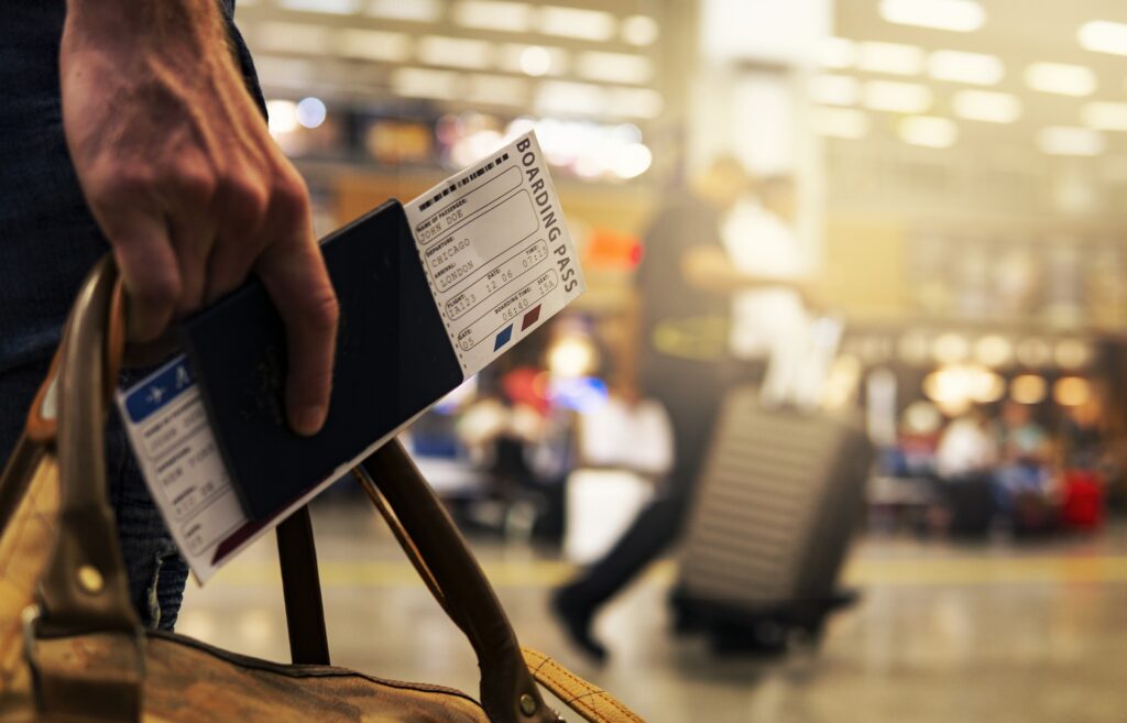 Hand holding his passport and boarding pass in the airport