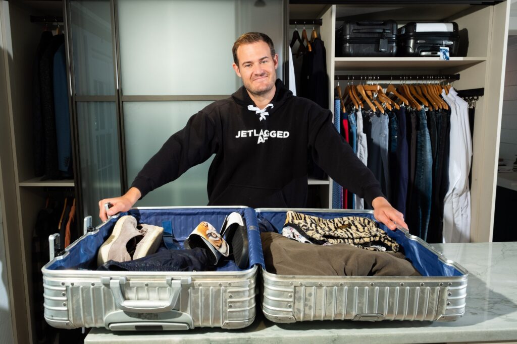 The Points Guy Brian Kelly standing behind a packed suitcase (Photo Credit: The Points Guy)