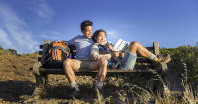 Happy gay hikers resting on bench. (Photo Credit: iStock)