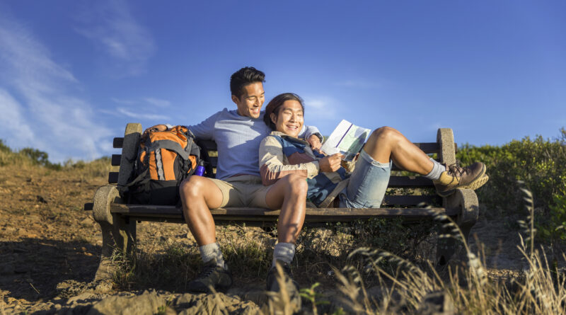 Happy gay hikers resting on bench. (Photo Credit: iStock)