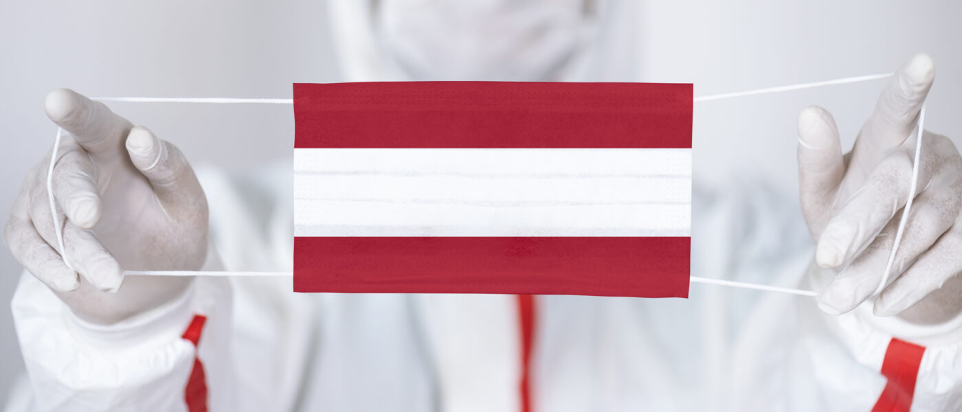 Healthcare personnel is holding Austrian Flag shaped surgical mask.