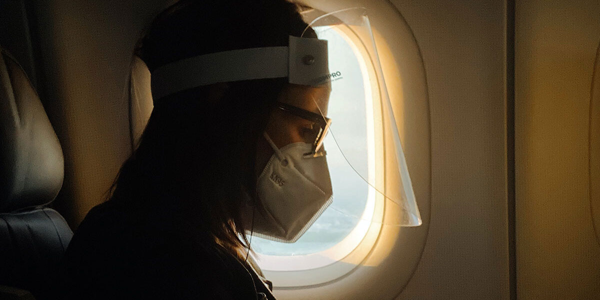 Woman on airplane with face shield and mask