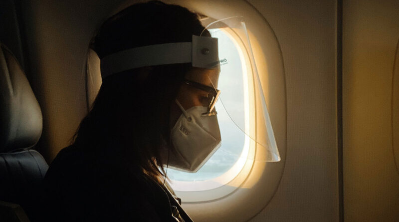 Woman on airplane with face shield and mask