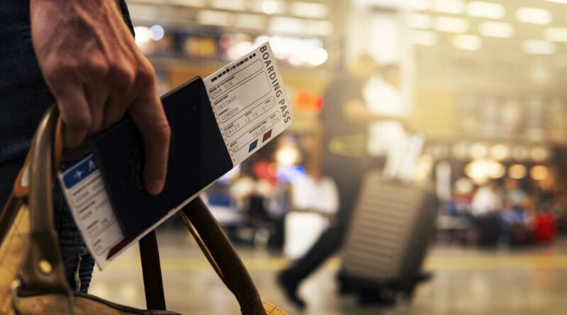 Close photo of man carrying passport and airplane ticket in an airport