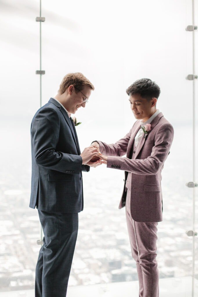 Eric and Carlo exchanging rings during their wedding ceremony on the Ledge (Photo Credit: Skydeck Chicago)