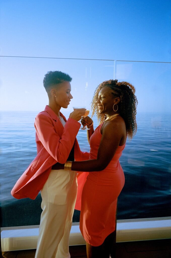 Travel influencers and LGBTQ+ activists, Aisha and Lexie, have a cocktail together overlooking the sea onboard Celebrity Apex. (Photo Credit: Giles Duley / Celebrity Cruises / AIPP)