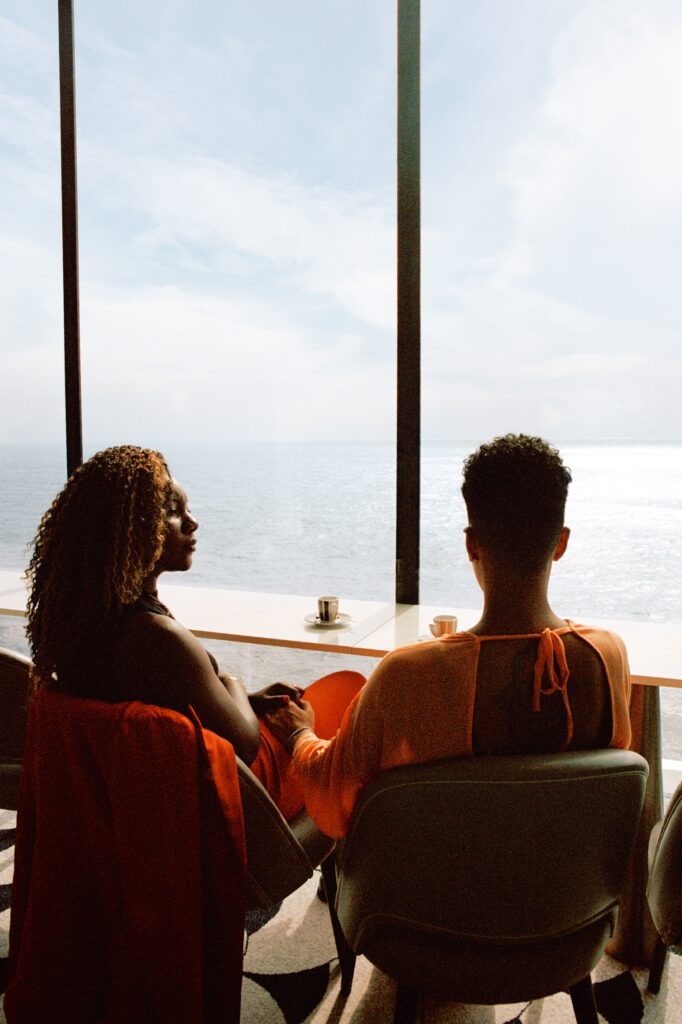 Travel influencers and LGBTQ+ activists, Aisha and Lexie, have a coffee together in The Retreat Lounge on Celebrity Apex, overlooking the sea. (Photo Credit: Giles Duley / Celebrity Cruises / AIPP)
