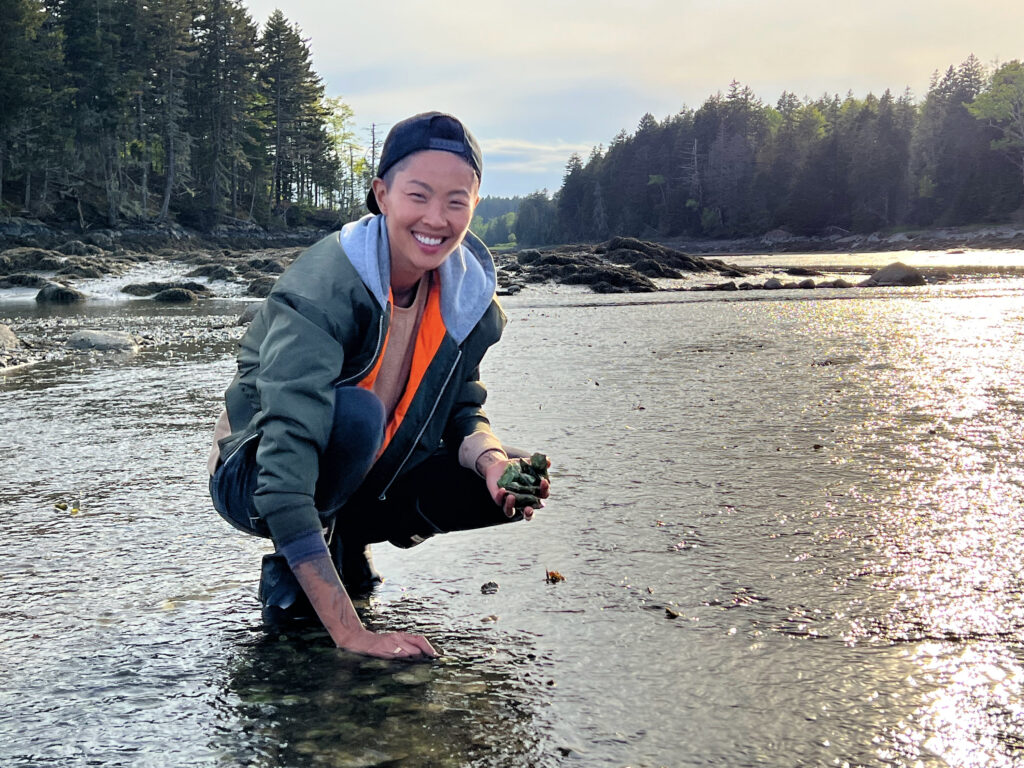 Chef Kristen Kish poses with freshly caught oysters in hand at the estuary in North Haven, Maine. (Photo Credit: National Geographic/Missy Bania)