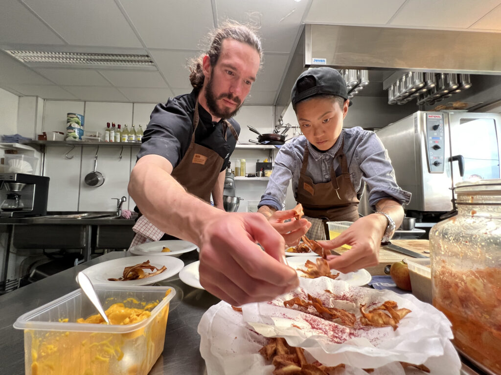 Chefs Rogier Jensen and Kristen Kish plate the sorbet in the kitchen at Isfjord Radio in Svalbard, Norway. (Photo Credit: National Geographic/Missy Bania)