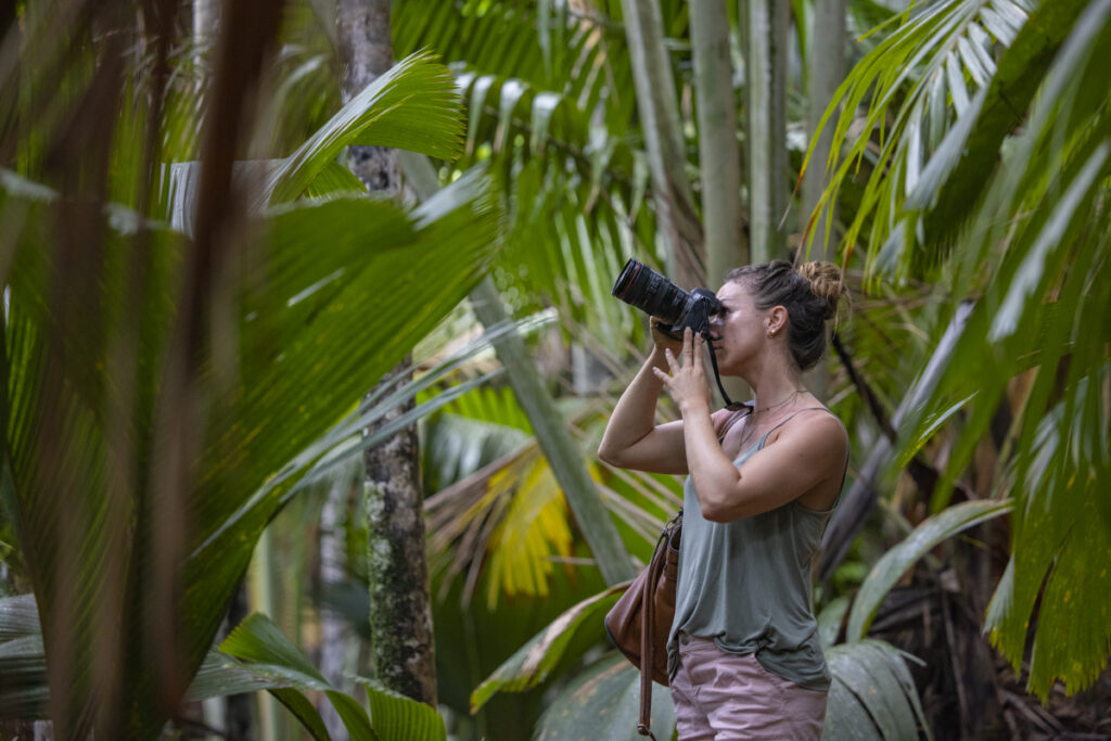 Young woman with camera in Vallée De Mai Nature Reserve, a UNESCO World Heritage Site on Praslin Island.(Photo Credit: Variety Cruises)