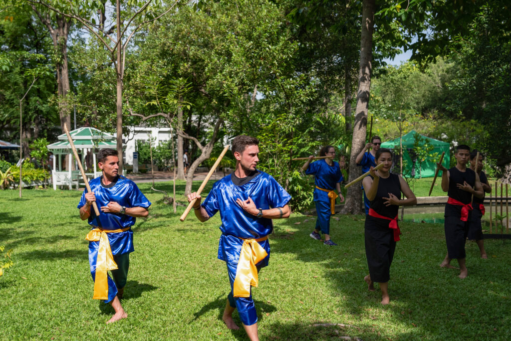 Joe and Ian practice a sword routine with sticks before wielding real swords for a challenge in Thailand. (Photo Credit: Nicolas Axelrod/CBS)